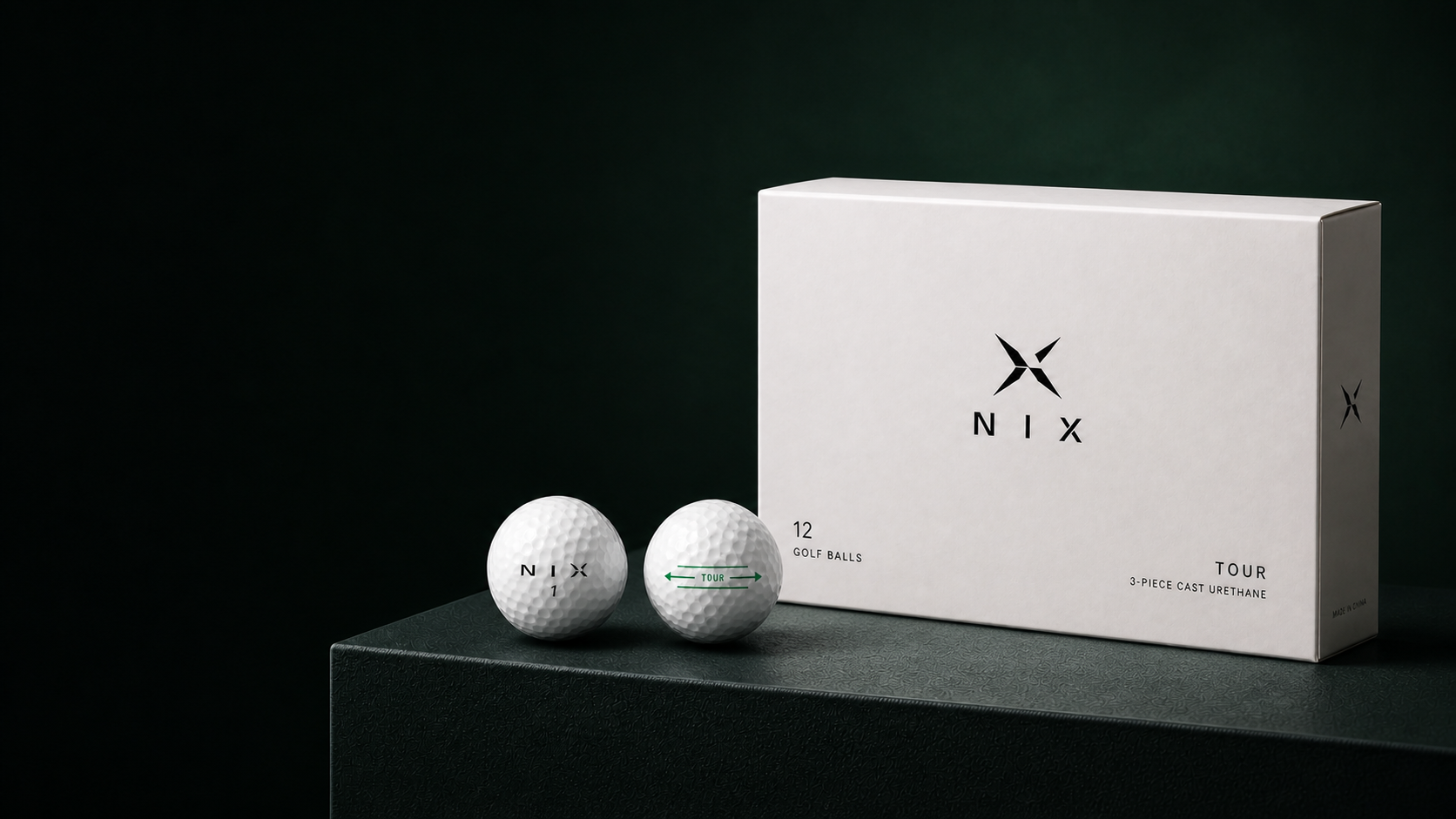 Latest NIX Tour golf ball box and two golf balls in a dark green studio